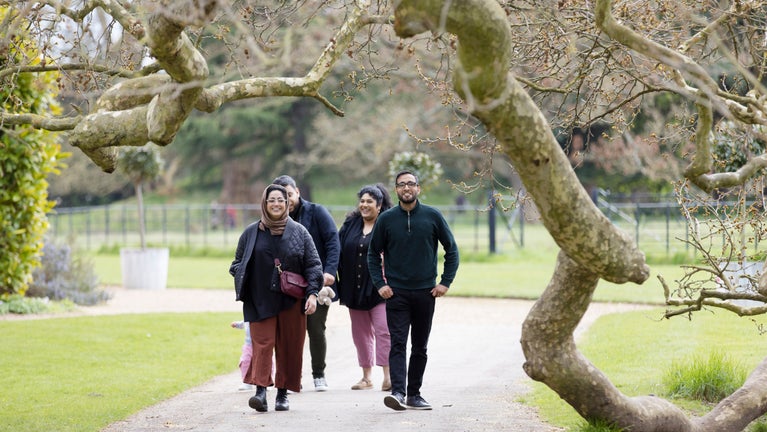 A family walking through Osterley Park, framed by tree brances
